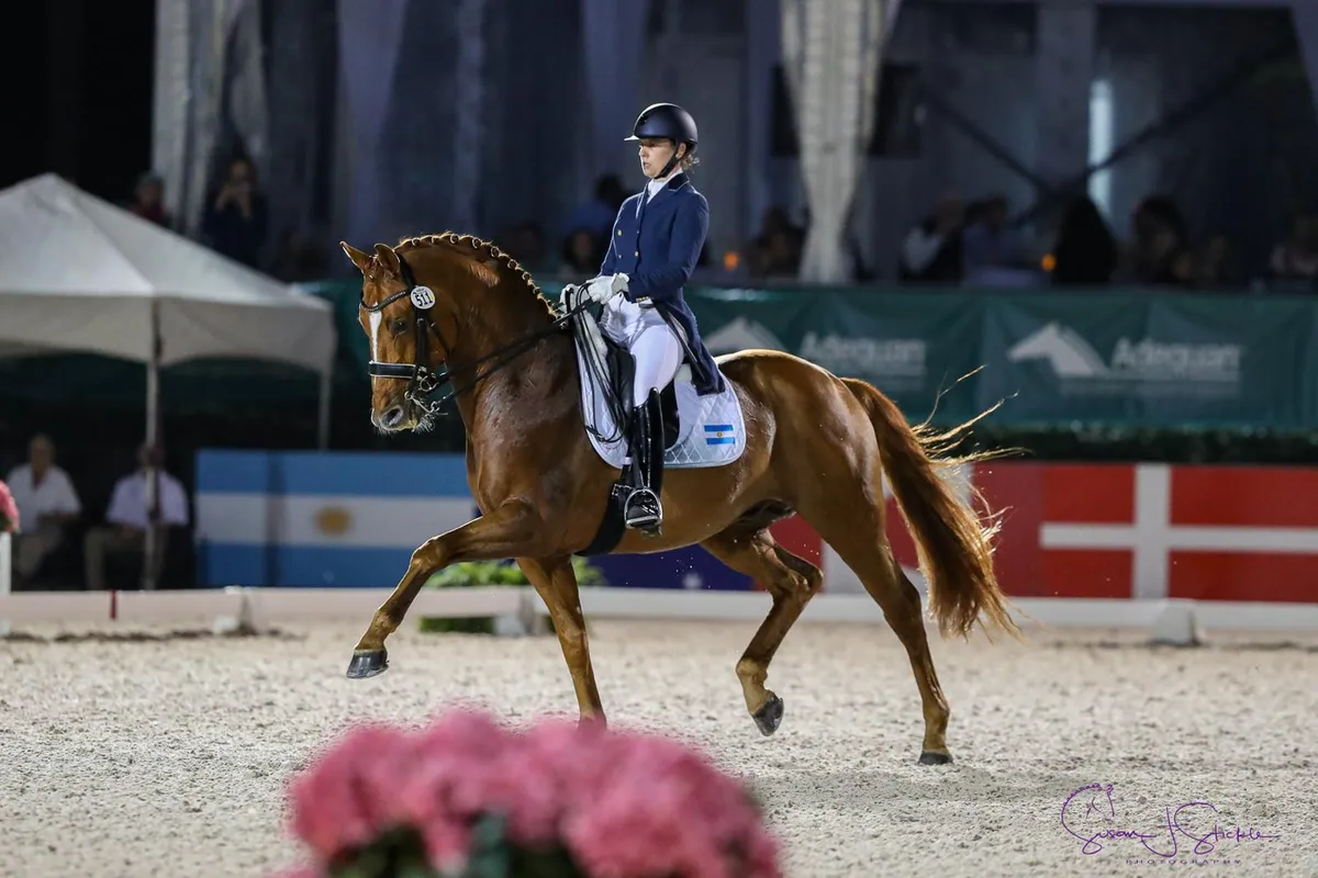 Mica Mabragaña competing at night in a sand arena with Adequan banners